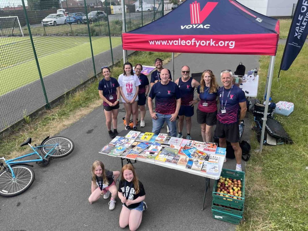 Running books donated by Kevin Moseley on a table at the Selby Fun Day, with Vale of York members and children standing behind