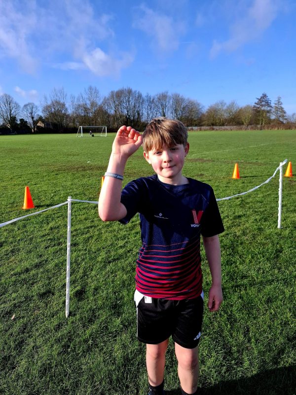 A Vale of York junior at Brayton Academy junior parkrun raising his arm to show his 100 junior parkrun wristband.